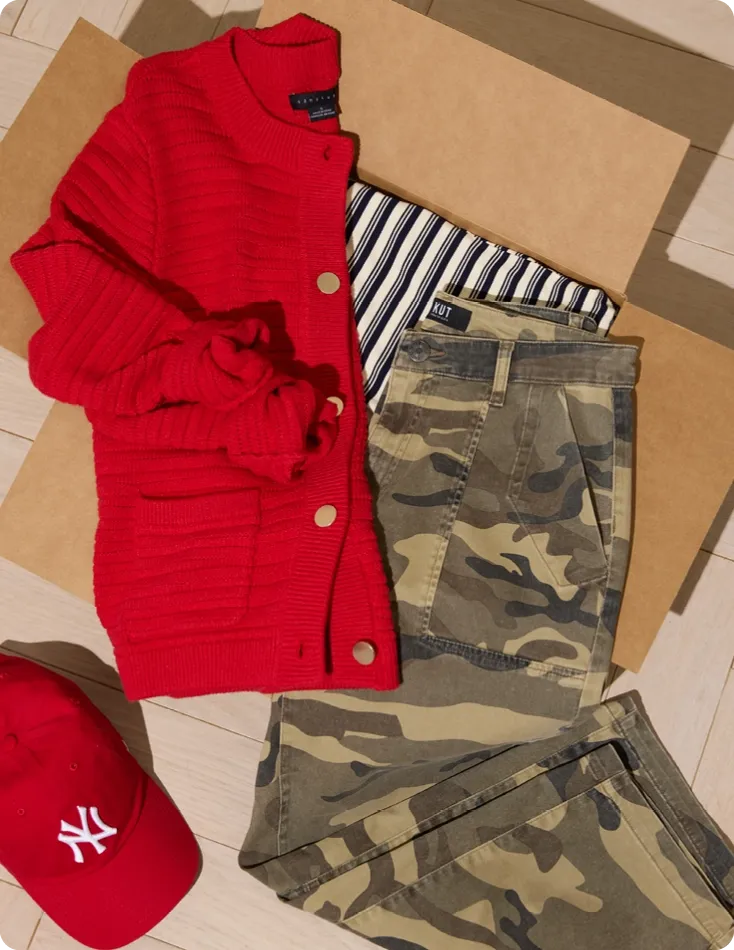 A flat lay featuring a red cardigan, striped shirt, and camo print pants, offering inspiration on what to wear with camo print. The combination of the vibrant red and the camo print showcases a playful mix of patterns and colors, perfect for a stylish yet comfortable look.