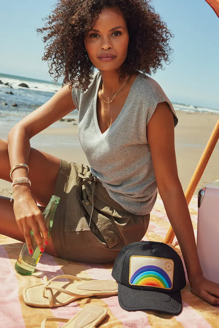 A woman on the beach wearing a grey t-shirt and a utility skirt, illustrating a casual summer outfit featuring utility pants style elements.